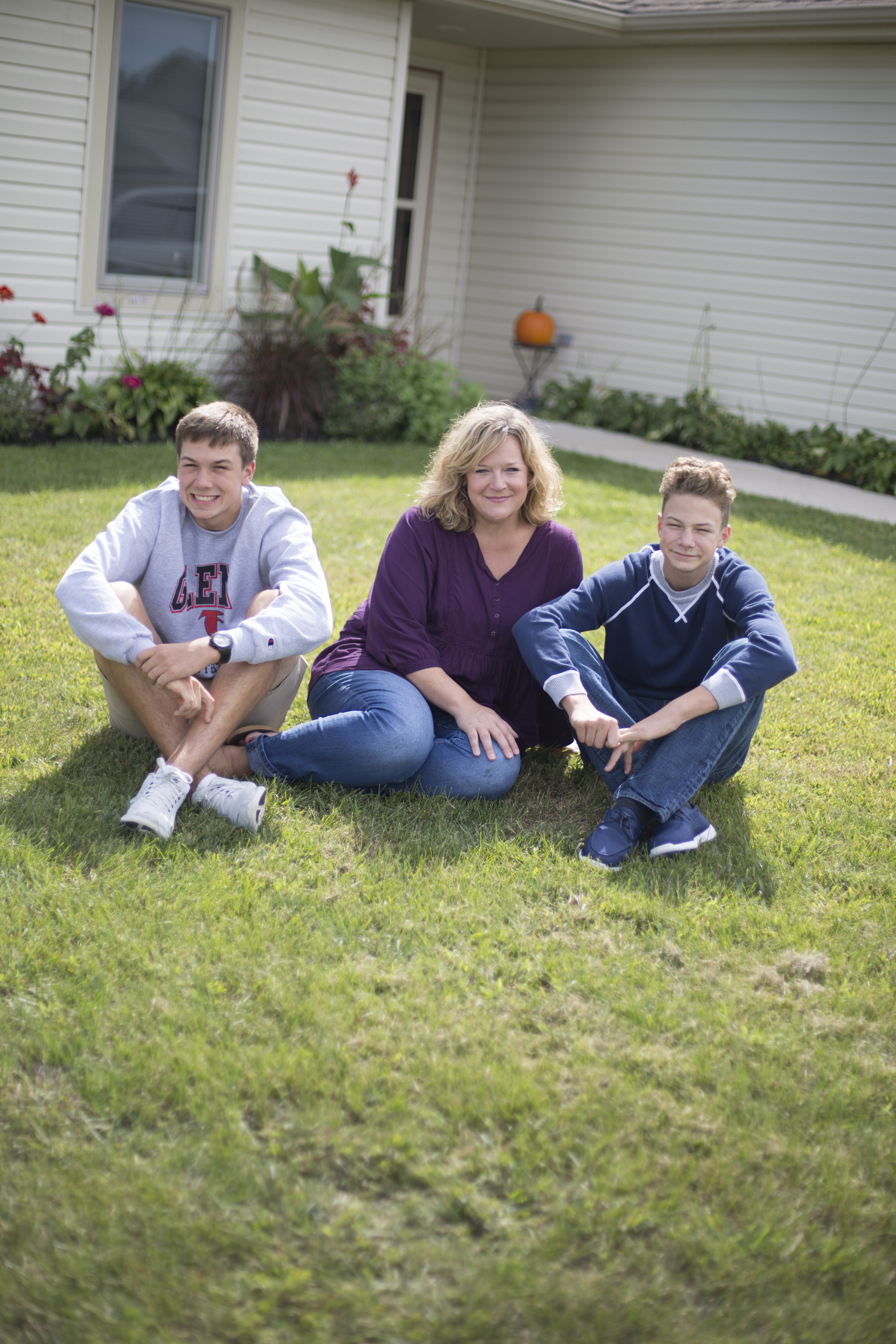 Mother with two sons sitting on their lawn