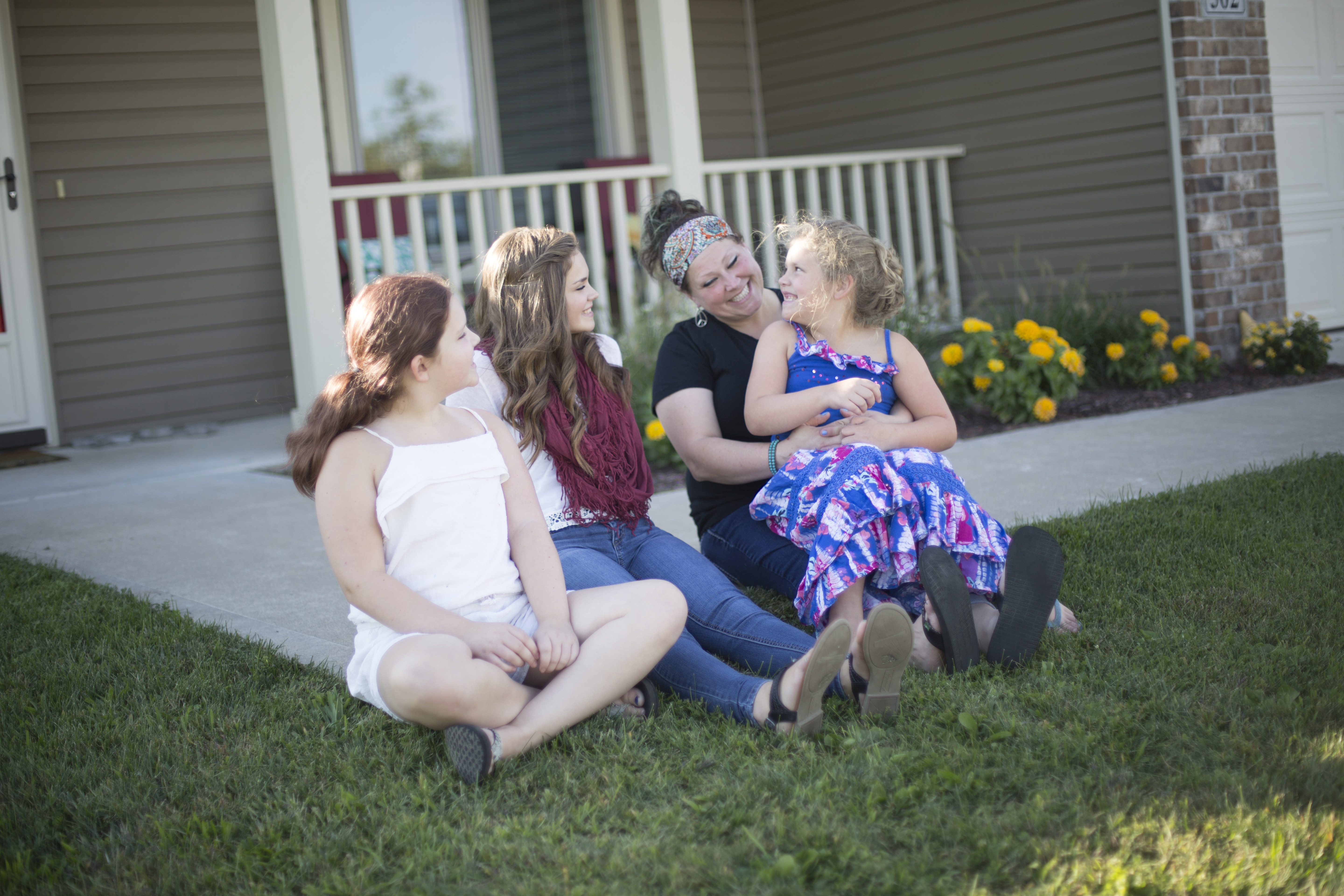 Three daughters sit with mom on their front step