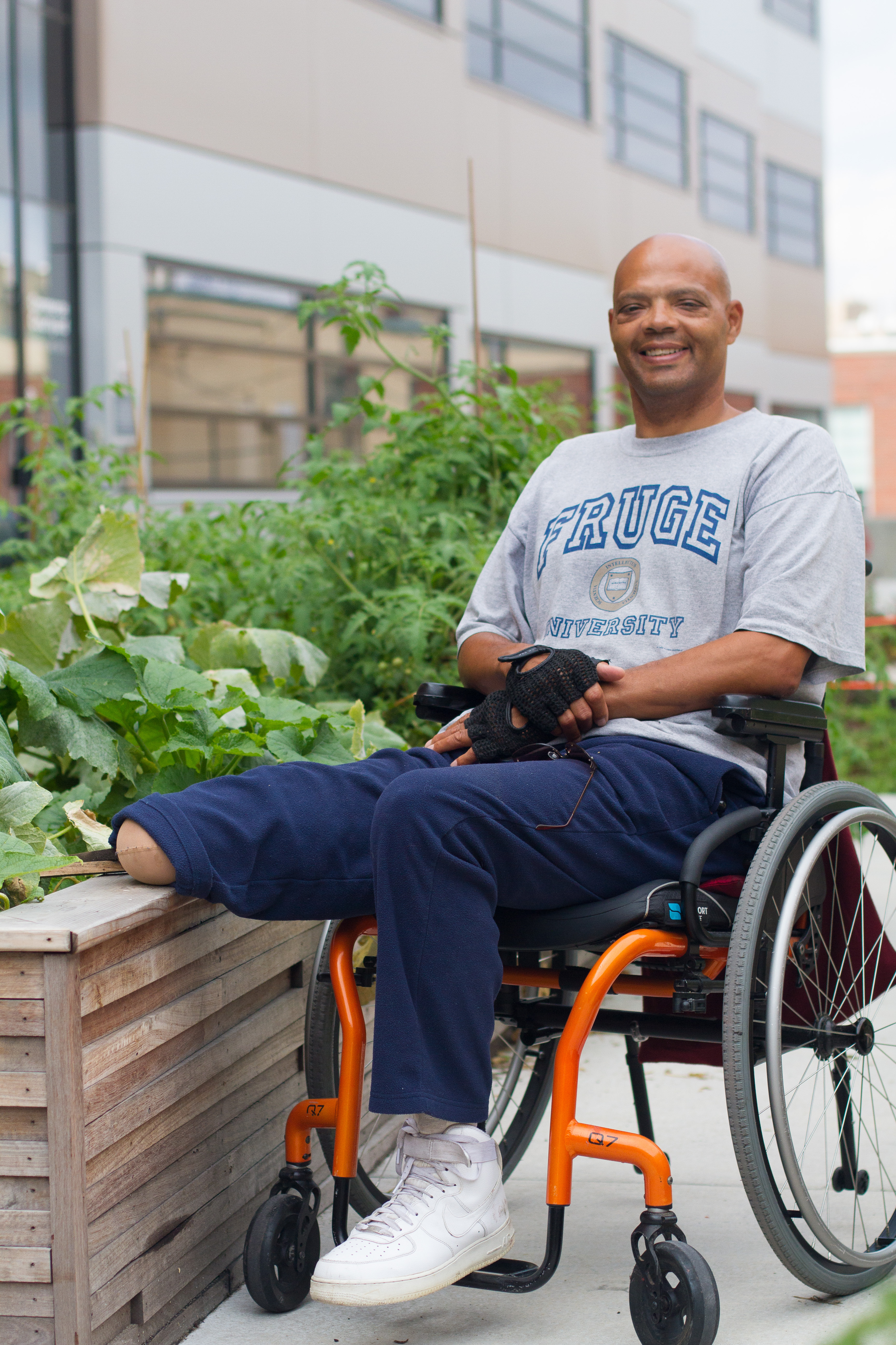Man in wheelchair resting his leg on the garden wall