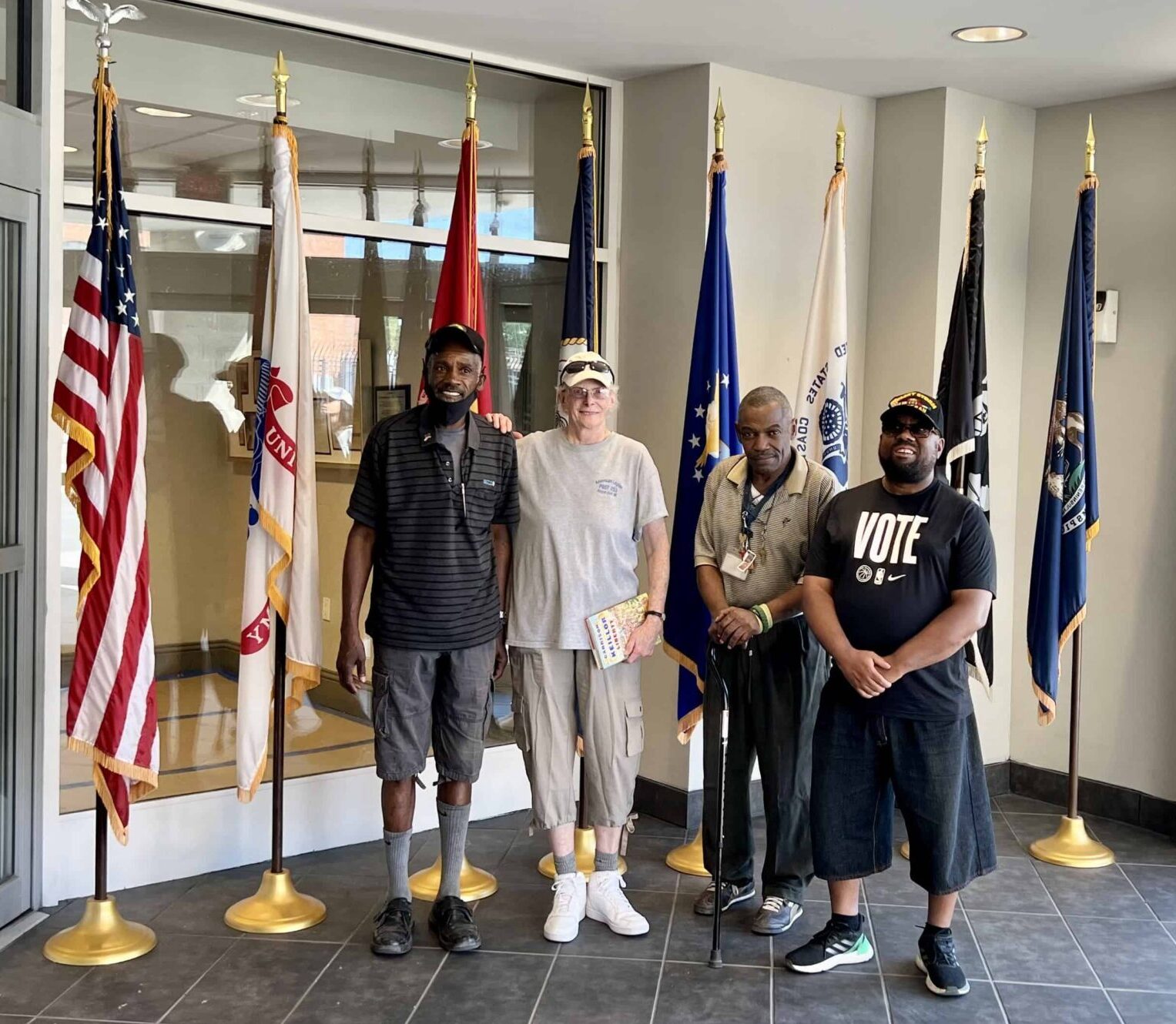 Four veterans in front of military flags