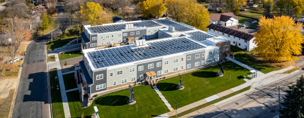 Affordable housing building with solar panels on roof and solar flowers in lawn