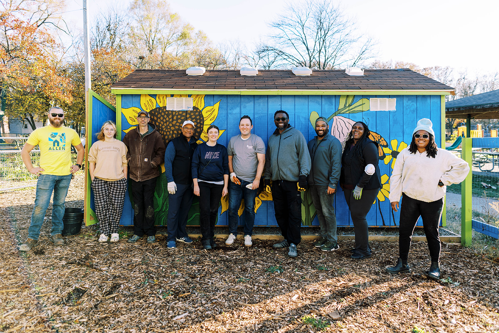 9 Cinnaire staffers outside a shed at Allen Place food garden