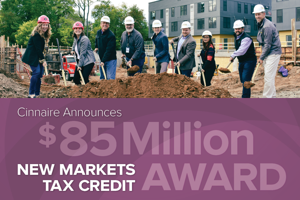 graphic announcing $85M NMTC Award with image of people with shovels at a groundbreaking event