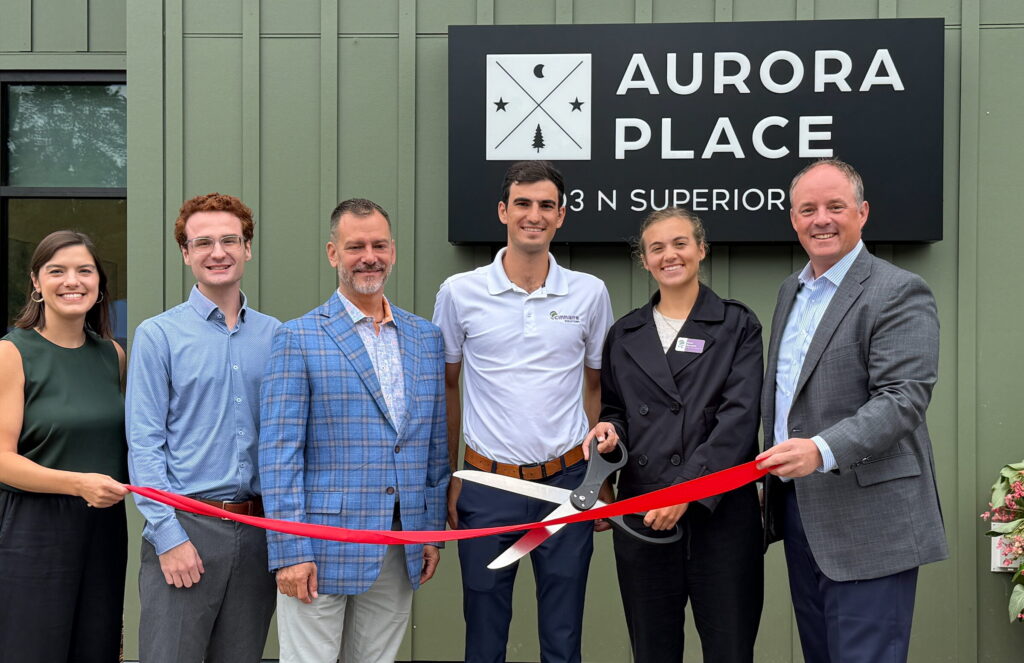 Cinnaire staff members condut ribbon cutting in from of Aurora Place sign